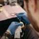 Tatuatore con guanti prepara la macchinetta con grip protetto