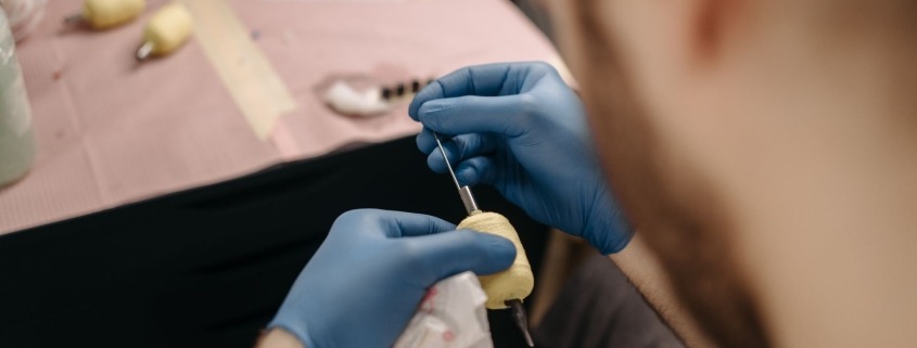 Tatuatore con guanti prepara la macchinetta con grip protetto