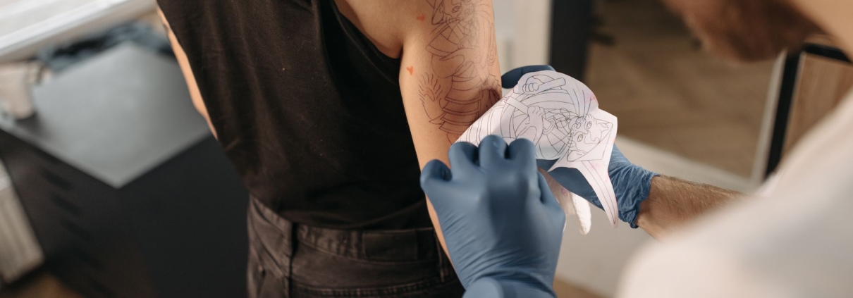 Tatuatore applica lo stencil sul braccio di una cliente