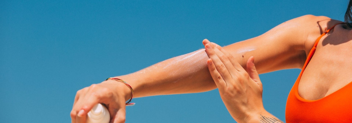 Crema solare applicata su un braccio tatuato in spiaggia
